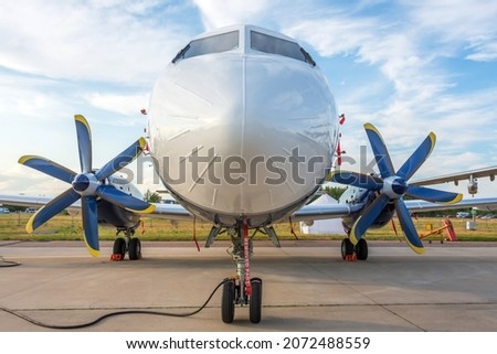 New turboprop aircraft parked at the airport, view straight ahead. Connected to ground power Royalty-Free Stock Photo #2072488559