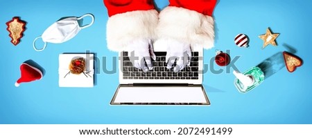Santa Claus using a laptop computer with a mask and a sanitizer bottle from above