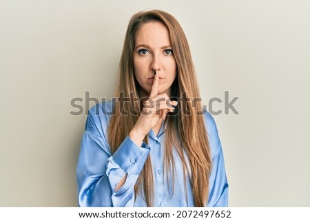 Young blonde woman wearing casual blue shirt asking to be quiet with finger on lips. silence and secret concept. 
