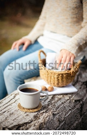 a woman holding cup of tea or coffee on a autumn leaves background