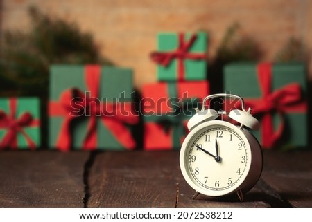 Alarm clock and Christmas gifts on wooden table and background