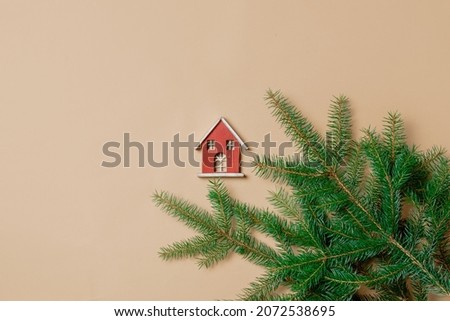Little toy house and spruce branch on stark white color background. Above view
