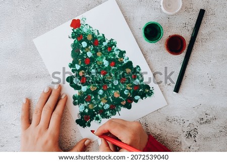 DIY Making greeting card Handmade crafts on holiday for children. Paint with fingers Merry Christmas tree. Top view. Step by step. Do it yourself. Happy New Year xmas tree decoration