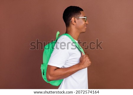 Profile side photo of young afro guy hold bag learning courses look empty space isolated over brown color background