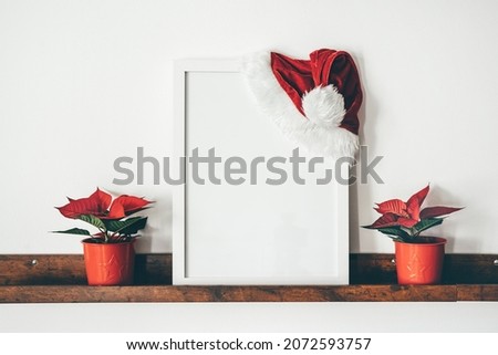 Image of mock up scene with white picture frame on brown shelf against white wall. Copy space