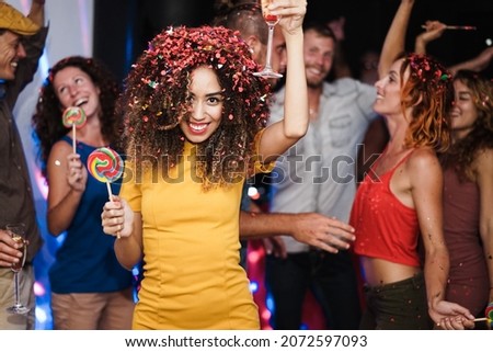 Young multiracial friends having fun cheering and drinking champagne at party night club - Focus on african girl face