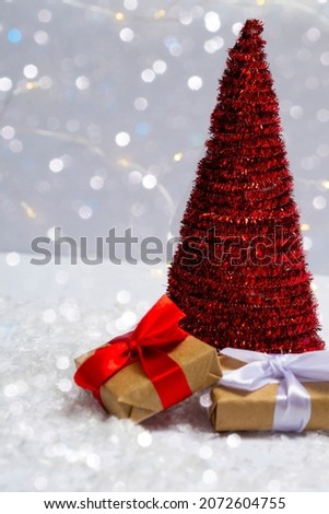 Christmas tree with gifts on the snow against a background of bright bokeh lights. Minimal concept of postcard, invitation card. Close up with copy space. Vertical photo