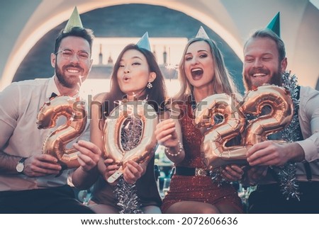 Men and women celebrating the new year 2022 Royalty-Free Stock Photo #2072606636