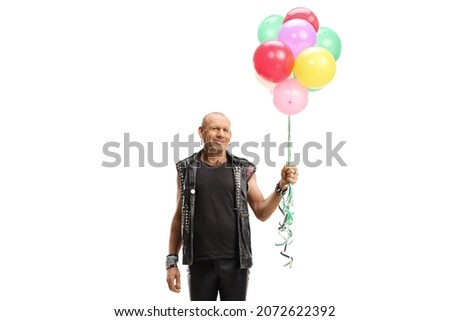 Punk man in leather clothes holding a bunch of colorful balloons isolated on white background