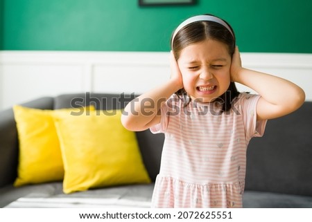 I don't want to listen to my parents. Upset little girl covering her ears because of screaming and loud sounds at home  Royalty-Free Stock Photo #2072625551