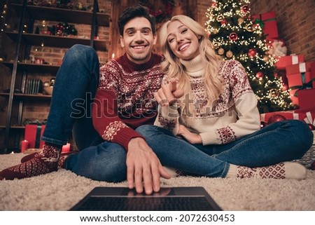 Portrait of two cheerful handsome beautiful girlfriend boyfriend watching web video film movie pointing newyear indoors