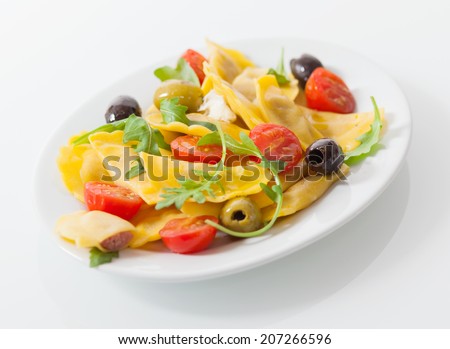 Delicious savory Italian ravioli salad with stuffed ravioli pasta, fresh rock and cherry tomatoes and a variety of olives , close up low angle view on a plate