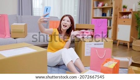 Happy asian woman receive packing parcel after online shopping at home and she takes selfie with new shoes in opening delivery box