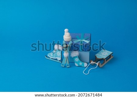 Hat, skates, socks, sled and gift box on a blue background. Accessories for winter sports and recreation.