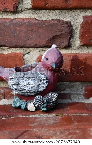 Cardinal statue by a brick wall