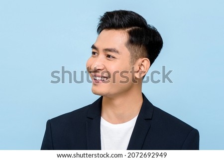 Young Asian man smiling and looking sideways in isolated light blue color background Royalty-Free Stock Photo #2072692949