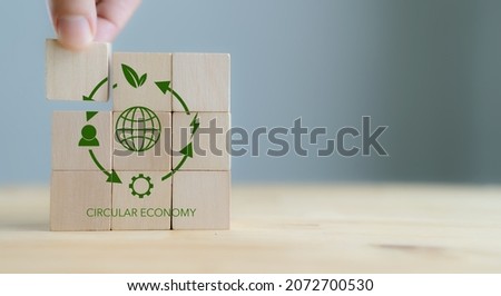 Circular economy concept, recycle, environment, reuse, manufacturing, waste, consumer, resource. 3rd.Sustainable development. Hand put wooden cubes; the symbols of circular economy on grey background. Royalty-Free Stock Photo #2072700530