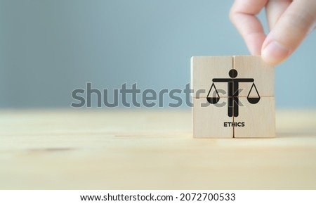 Business ethics concept. Business moral principles concept.  Hand holds the wooden cubes with "ETHICS" symbols on grey background and copy space. Banner for business integrity, good governance policy.