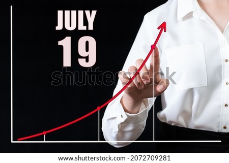 19th day of july. Businesswoman's hand pointing to the graph and a calendar with the date of 19 july. Business goals for the day. Summer month, day of the year concept.