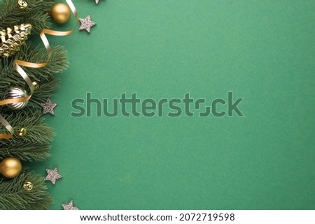 Top view photo of gold and silver christmas tree balls toy cone shiny stars small bells and serpentine on pine twigs on isolated green background with copyspace