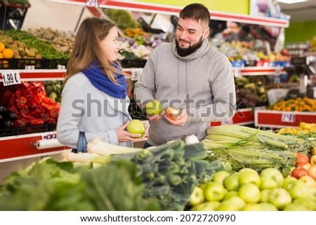 Glad couple choosing vegetables in grocery shop. High quality photo