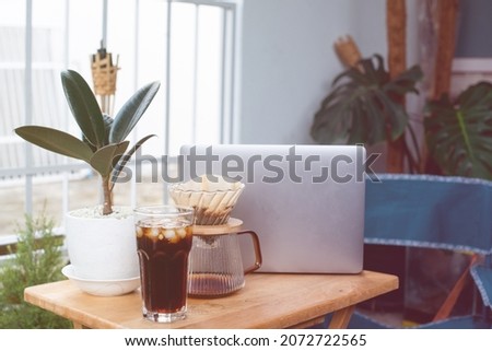 Laptop on wooden table coffee cup drip coffee and plant working at home freelance