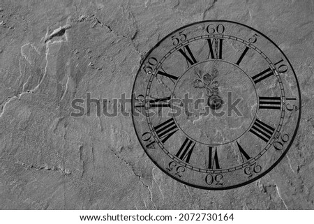 black clock on stone wall background with empty copy space for inscription. Vintage clock with Roman and arabic numeral. wall clock-face dial rustical on beige wall in the apartment. happy new year