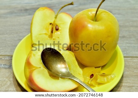 The picture shows baked apples and a spoon on a plate.