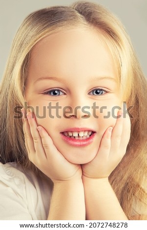 Girl kid with smile, face close-up, hands near face