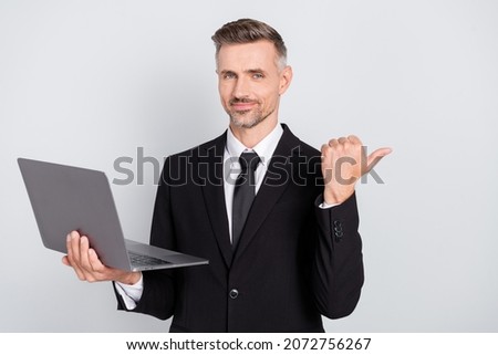 Photo of pretty handsome mature advisor dressed black suit holding modern gadget pointing thumb empty space isolated grey color background