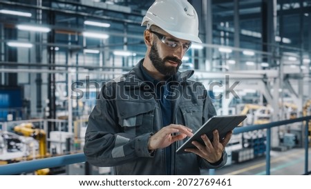 Car Factory Engineer in Work Uniform Using Tablet Computer. Automotive Industrial Manufacturing Facility Working on Vehicle Production with Robotic Arms Technology. Automated Assembly Plant. Royalty-Free Stock Photo #2072769461