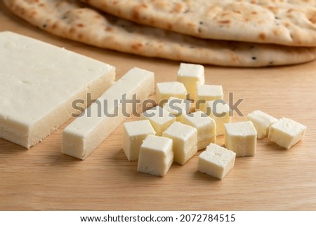 Slice of Indian paneer cheese, cubes and naan in the background  Royalty-Free Stock Photo #2072784515