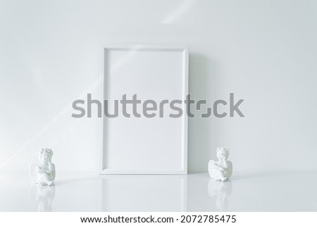 Vertical white blank frame mockup with porcelain Christmas angels. Wedding scene. Christmas, Valentine's day concept. Copy space. White predominance.