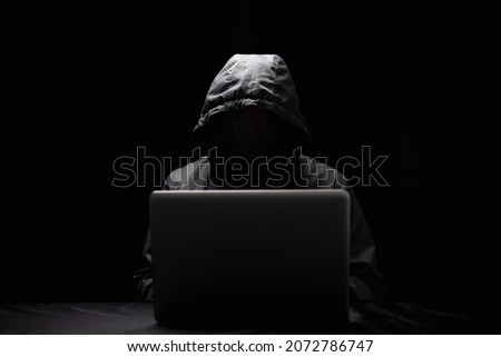 Hackers wear hoods to cover their faces. Hacking to steal important information. Use a computer to release malware viruses Ransom and harass organizations. He sitting in the dark room with neon light Royalty-Free Stock Photo #2072786747