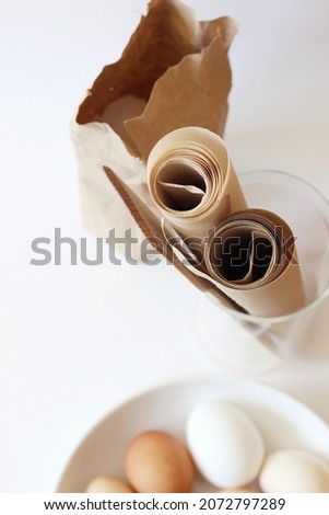 Baking Concept Background. Parchment Paper Rolls, Wooden Utensils, Eggs on White Kitchen Table Space. Home Kitchen Design.
