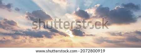 Beautiful fluffy clouds and rays of sunshine painted in dramatic colors at sunset Royalty-Free Stock Photo #2072800919