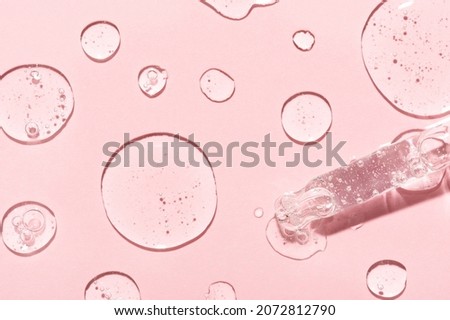 Drops of anti-aging emulsion and glass pipette tip on light pink surface close upper view. Skincare and dermatological procedures Royalty-Free Stock Photo #2072812790