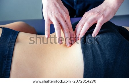 Physical therapist fixing sacroiliac joint or SI joint pain with his hands, myofascial release techniques for soft tissue treatment Royalty-Free Stock Photo #2072814290