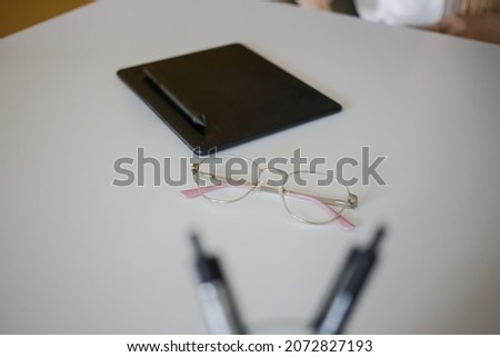 Glasses and tablet lie on a white table in the office