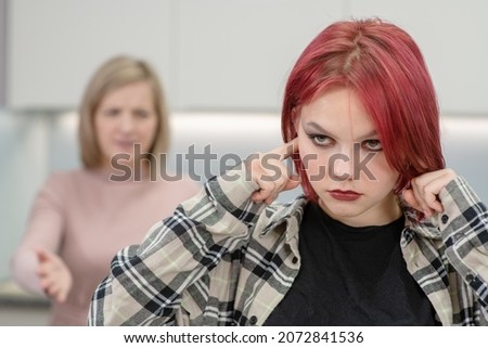 Mother scolds her teen daughter. Girl plugs her ears. Family relationships Royalty-Free Stock Photo #2072841536