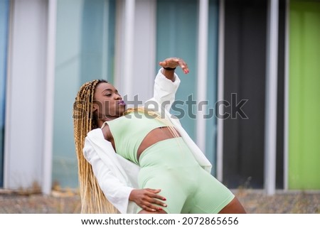 Photo with copy space of a african woman with braids dancing freestyle in front of a modern building