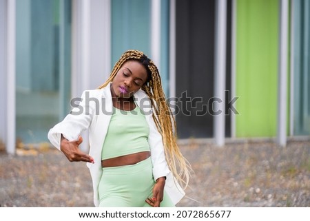 Photo with copy space of a african woman with braids dancing hip hop in front of a modern building