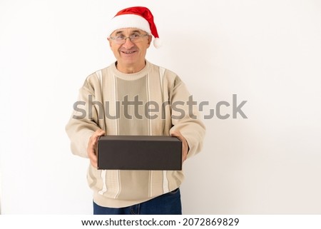 Smiling happy elderly man with a christmas present. Isolated over white background
