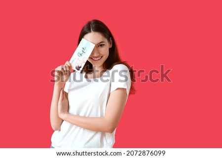 Young woman with gift voucher for massage on color background