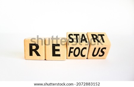 Refocus and restart symbol. Businessman turned cubes and changed the word 'refocus' to 'restart'. Beautiful white table, white background. Business refocus and restart concept. Copy space.