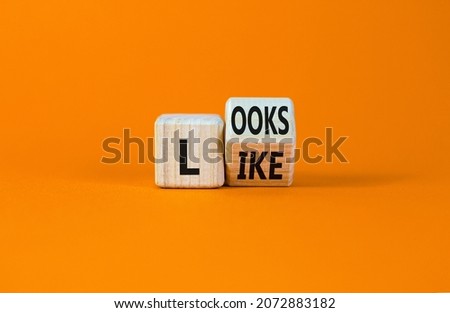 Looks like symbol. Turned a wooden cube with words 'Looks like'. Beautiful orange background. Business, popular quotes and looks like concept. Copy space.