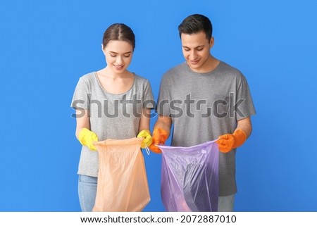Young couple with garbage on color background