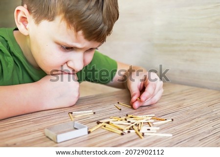 the child holds a lit match and it burns with a flame Royalty-Free Stock Photo #2072902112