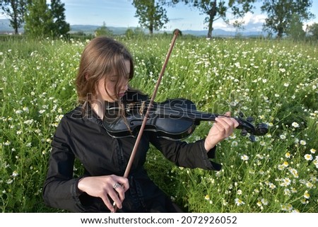 a girl in a black dress with a black violin,