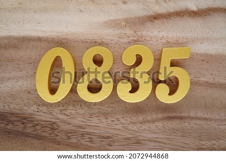 Golden Arabic numerals 0835 on a dark brown to white wood grain background.